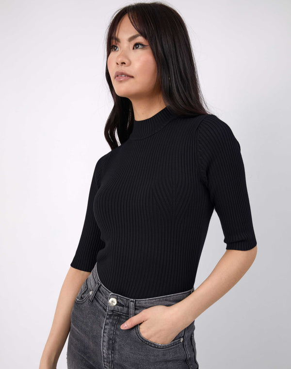 model has hand in pocket wearing the meg ribbed mid sleeve bodysuit in black with grey jeans