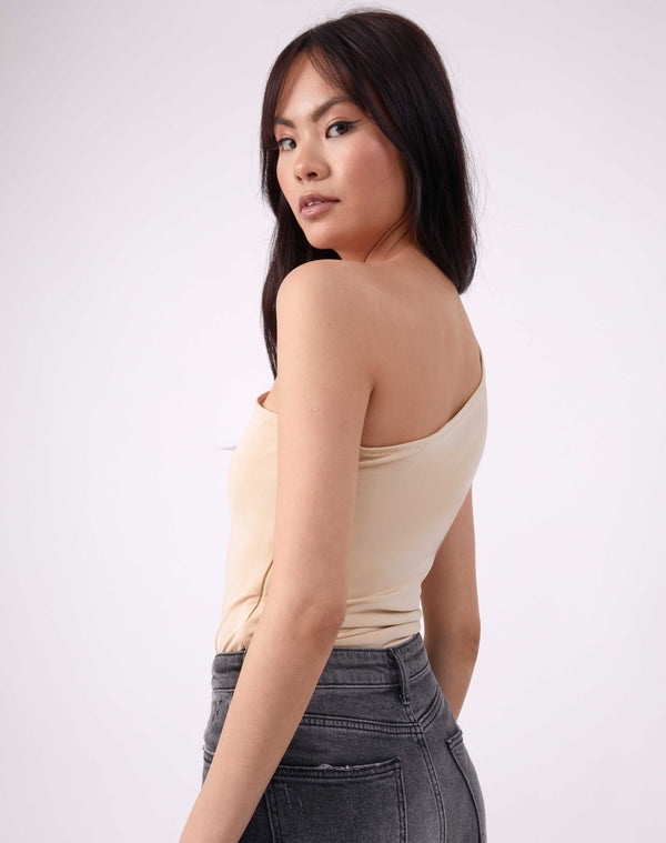 model looks over her shoulder in isla birch one shoulder bodysuit worn with grey jeans