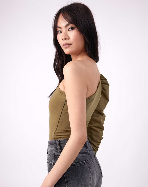 model looks over one shoulder to camera wearing the monet olive green one shoulder bodysuit with grey jeans