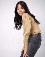 model bends forwards with hands on her knees the nina balloon sleeve knit top in beige and grey jeans