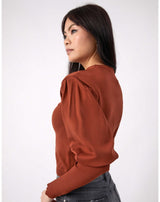 model looks over her shoulder while wearing the Nina Brown Balloon Sleeve Knit Top with grey jeans