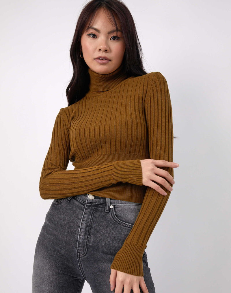 the model hold one of her arms while wearing the Vlona Olive Turtleneck Ribbed Knit with grey jeans