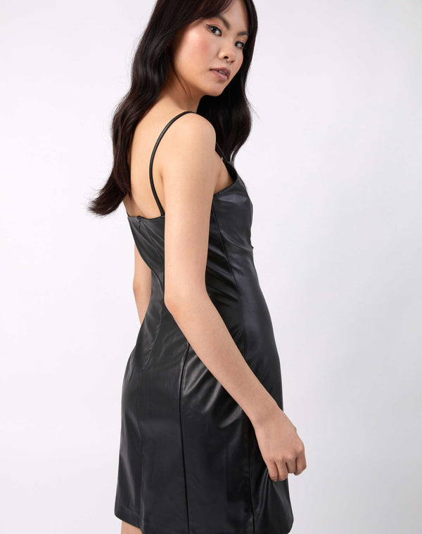 the model looks over her shoulder showing the back of the Ray Faux Leather Mini Dress in Black