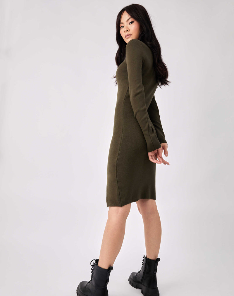 full length image of model from the back with her hands behind her in in the liana olive green roll neck knit midi dress with military boots