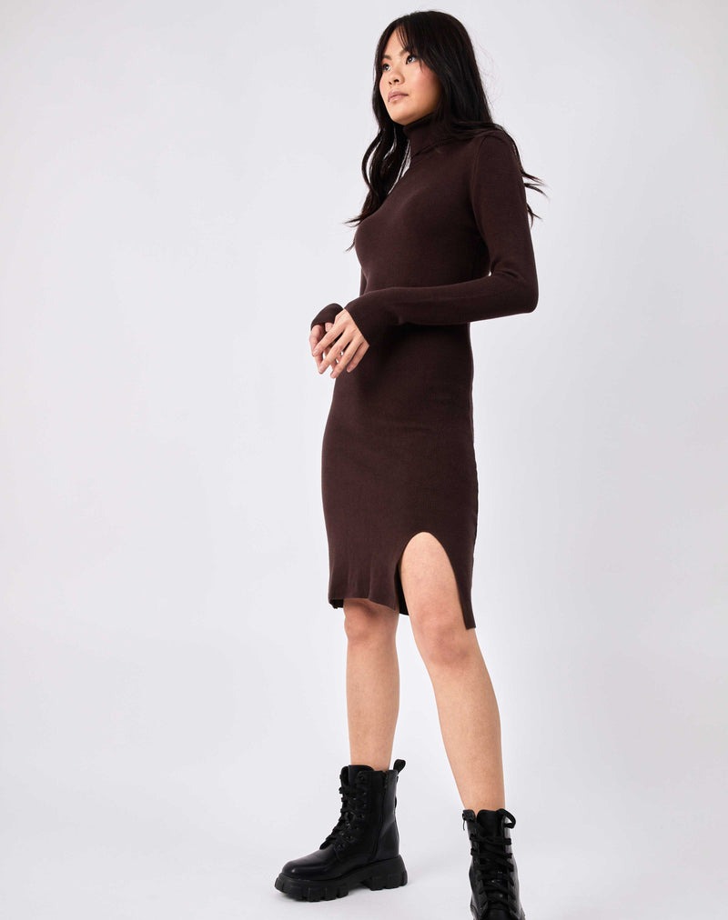 model looks off camera with hands in front of her in the liana brown roll neck knit midi dress with military style boots