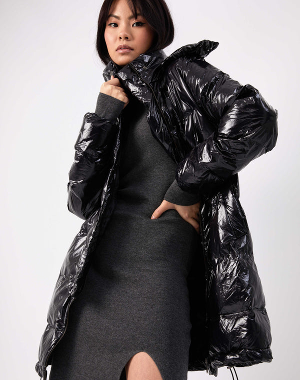 model wears the lola black shine longline puffer jacket over a grey knit dress