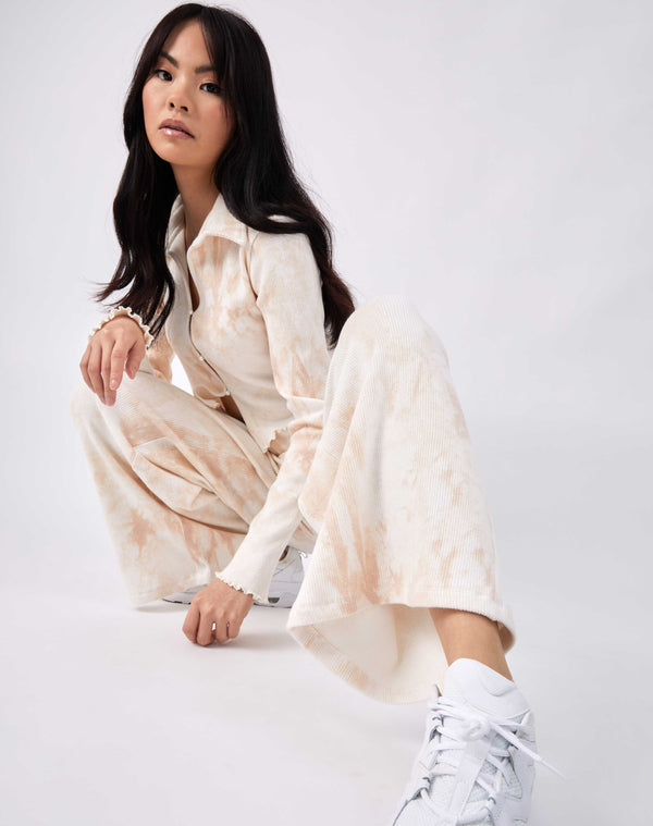 a model wears the amer ti dye wide leg trousers with matching top, while crouching down and looking at the camera