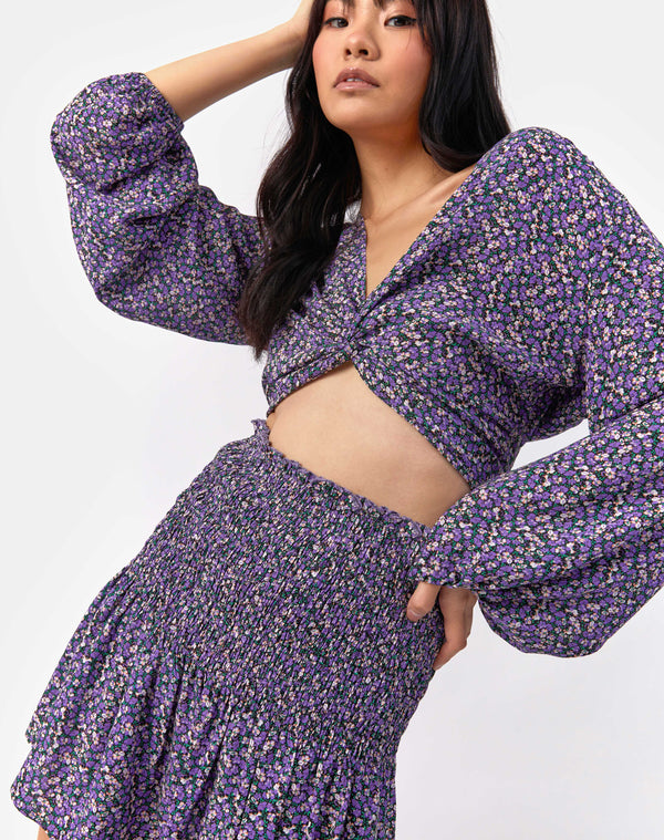 model holds her hand to her head while wearing the Una Shirred Skirt in Lilac Floral with matching top