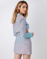 model looks over her shoulder wearing the Mona Iridescent Cropped Blazer with matching skirt