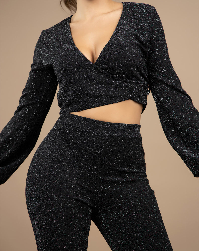 a cropped image of a model wearing a two piece black lurex set close up of the top in front of a beige background