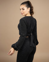 a shot of a model wearing a black lurex two piece, a shot from the back showing the tie from the top and the model looking over her shoulder