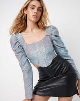 a cropped image of a model wearing the eve iridescent corset style top in pink and blue with a pu mini skirt
