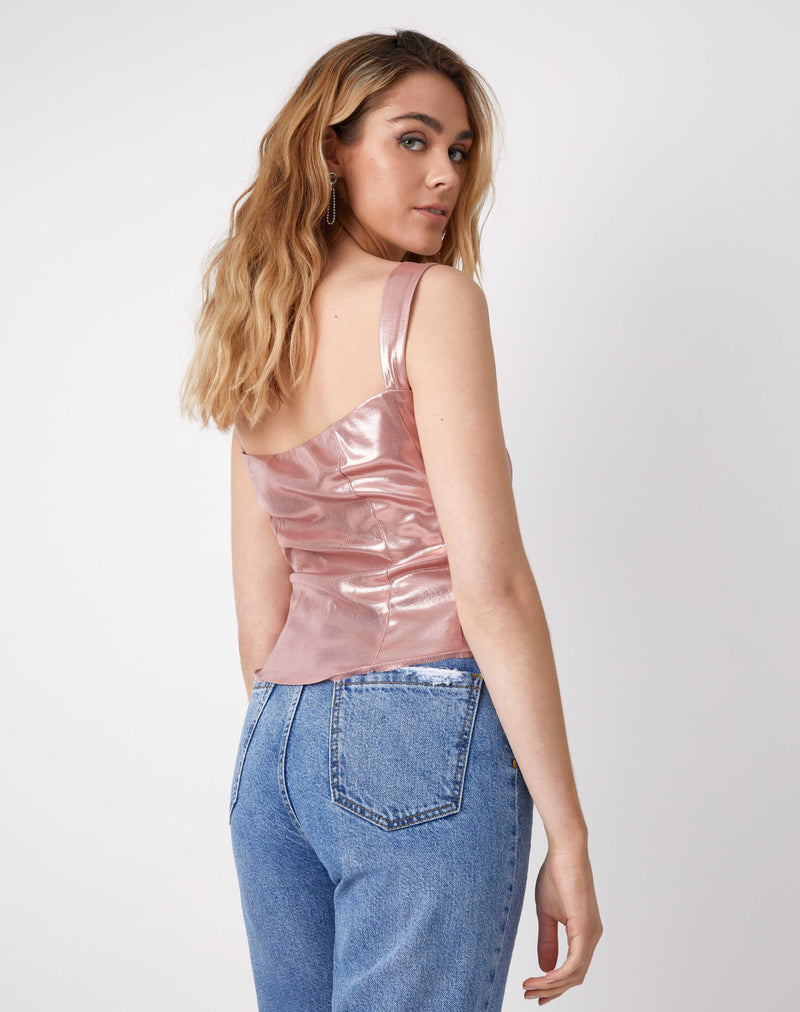 model looks over her shoulder while showing the back of the chi sparkly pink corset top with blue jeans