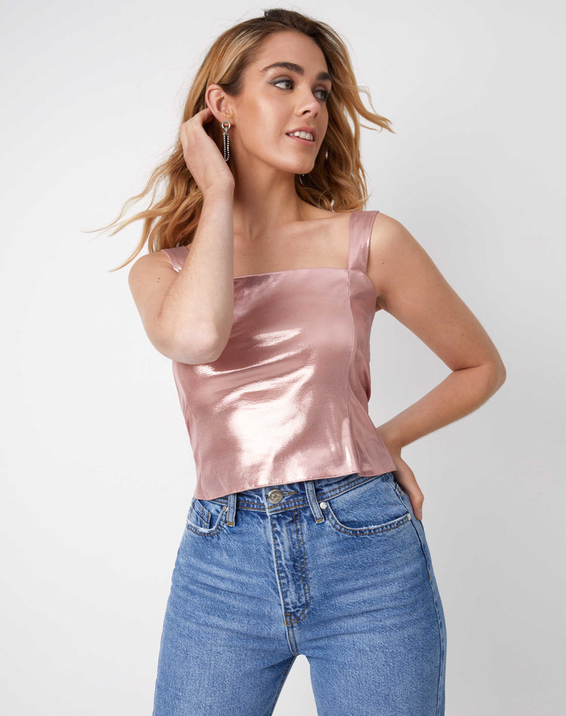model has her hand by her ear in the chi sparkly pink corset top with blue jeans