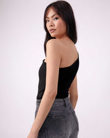 the model looks over her shoulder showing the back of the isla black one shoulder bodysuit with grey jeans