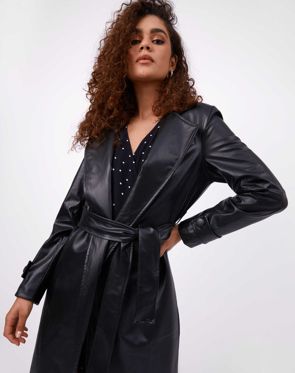 model has the coco faux leather coat on with belt tied over a polka dot dress