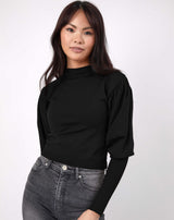 model smiles wearing the nina balloon sleeve knit top in black with grey jeans