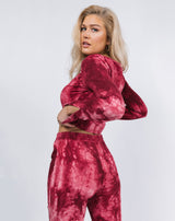 model turns away from the camera holding the hem of the Reign Red Tie Dye Cut Out Top with matching trousers