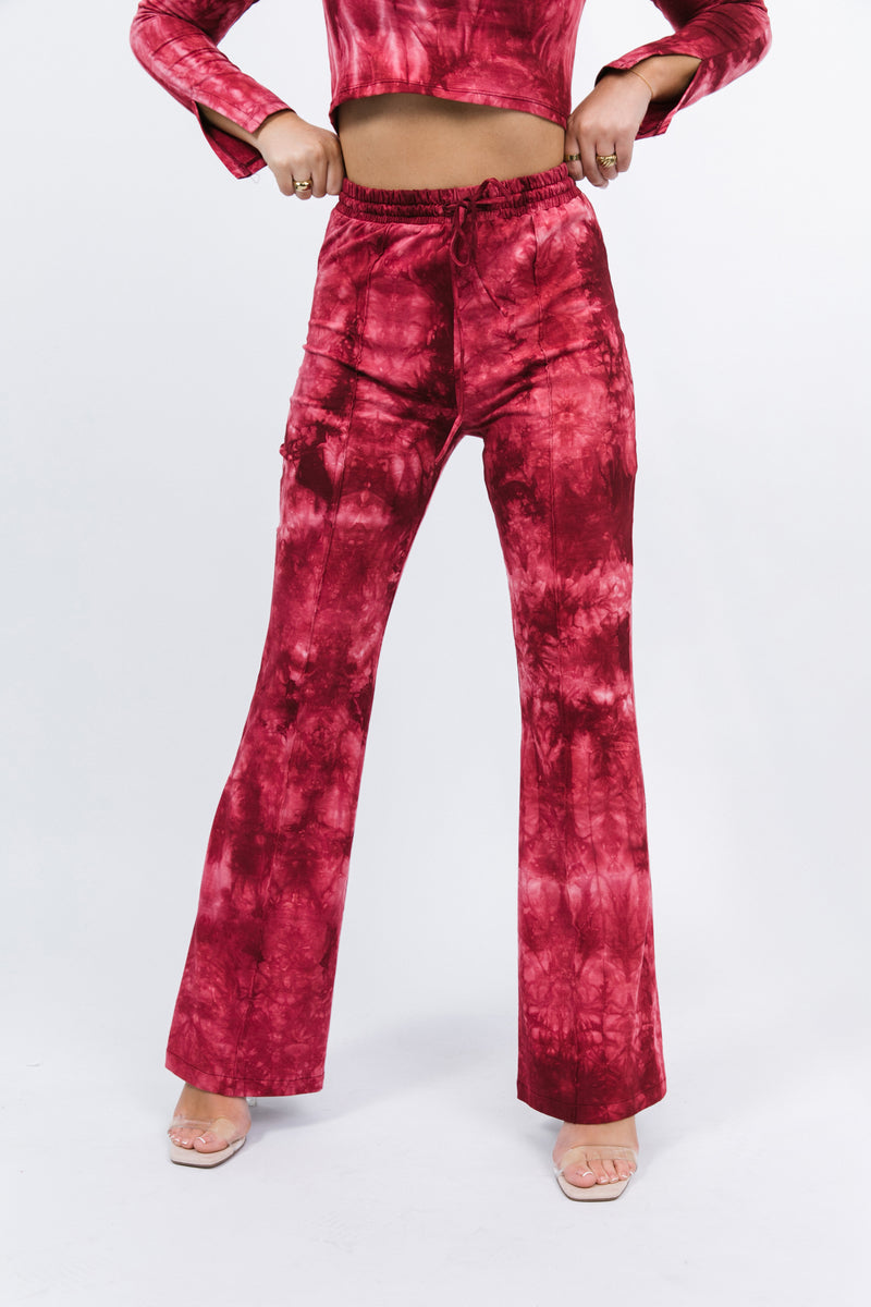 a close cropped in image of the Riley Red Tie Dye Flared Trousers with nude heels