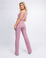 model looks over her shoulder while wearing the Laura One Shoulder Jumpsuit in Ribbed Blush
