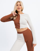 a cropped in image of the model holding her hand to the neck of the Foxy Two Tone Ribbed Button Front Top