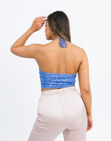 the model turns away showing the back of the Hera keyhole halterneck crop top in blue zebra with satin trousers