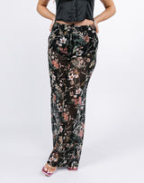 a close up cropped shot of the model wearing the lisa black floral wide leg trousers