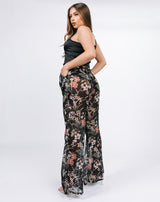 model shows the back of the lisa black floral wide leg trousers with a black satin corset and heels