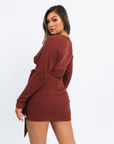 the model looks over her shoulder wearing the Lotta Wrap Mini Dress In Chocolate Fluffy Rib showing the back