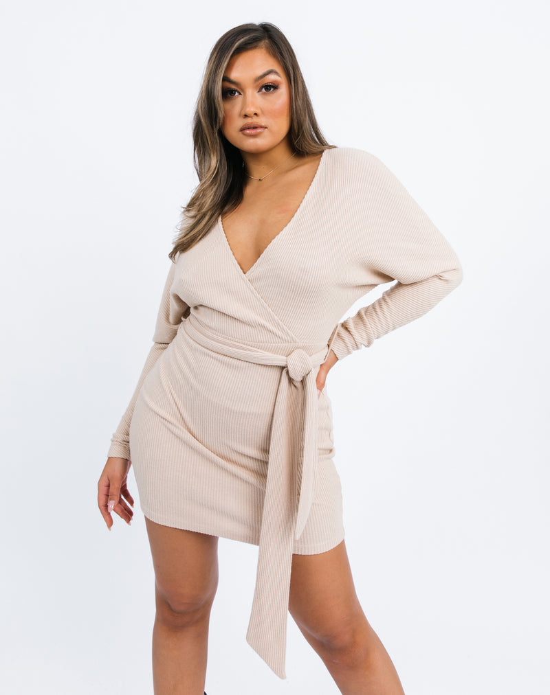 the model poses with her hand on her hip in a crop of the Lotta Wrap Mini Dress In Beige Fluffy Rib