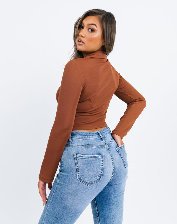 the model turns away from the camera to show the back of the Stella Chocolate Ribbed Button Up Top