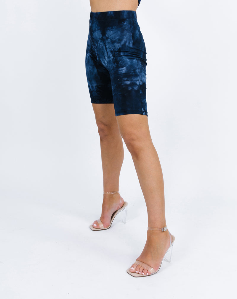 a side shot of the model wearing the Rosanna Blue Tie Dye Cycling Shorts and perspex nude heels