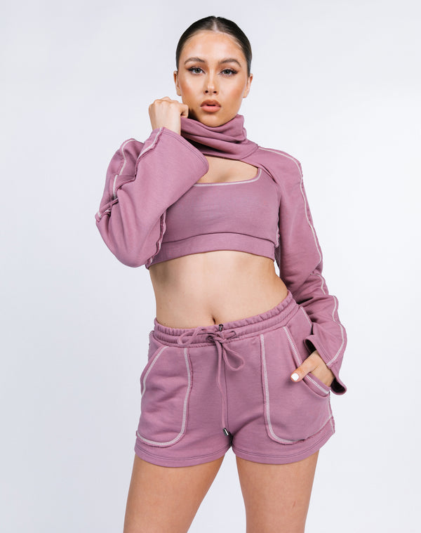 model holds the neck of the Janine Just Sleeves Jumper in blush with matching shorts and top