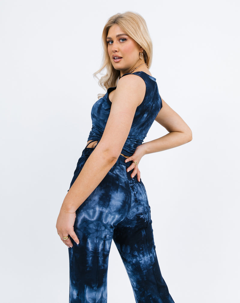 the model turns away from the camera showing the back of the Renee Blue Tie Dye Ruched Side Sleeveless Top and trousers