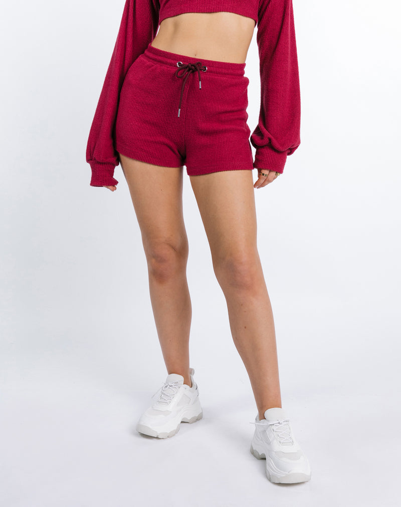 crop image of the model wearing the Becky Roft Ribbed Shorts in Raspberry with white trainers