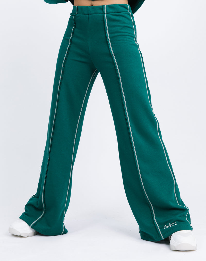 a close up cropped shot of the model wearing the Chantelle Contrast Stitch Logo Trousers in Forest Green with trainers