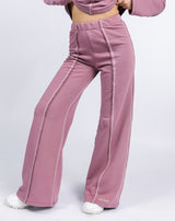 a cropped in close up image of the model wearing the Chantelle Contrast Stitch Logo Trousers in Blush with white trainers