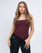 model poses in the chloe ruched bodysuit in grape with black satin joggers