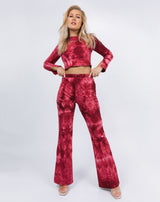 the model holds the waistband of her trousers with the Reign Red Tie Dye Cut Out Top and nude heels