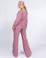 model looks over her shoulder while wearing the Chantelle Contrast Stitch Logo Trousers in Blush with matching top