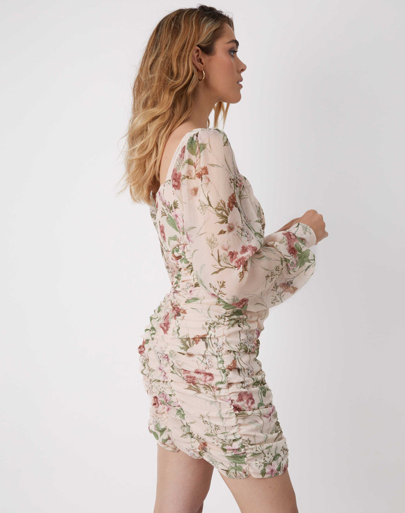 model faces sideways in the jana gathered floral mini dress with long sleeves and her hands in front of her