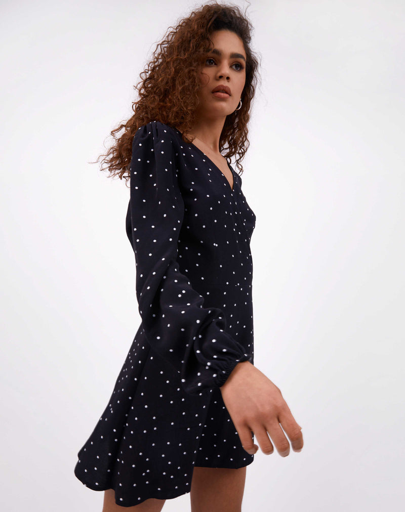 model wearing adina polka dot wrap dress while walking past camera