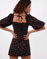 model has hands on her hips while facing away from the camera showing the tie back of the charlotte rose print puff sleeve dress in black